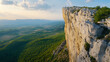 © sasisom - A wide-angle shot of a rock climber reaching the summit of a towering cliff, with an expansive view below