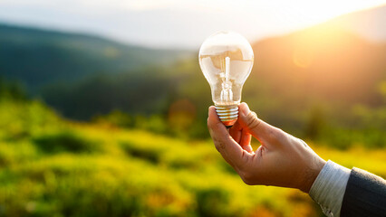 Wall Mural - Light bulb surrounded by green landscape.