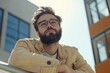© Oleksandr - Leaning On Railing. Young Bearded Man in Eyeglasses at Office Building