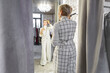 © Anna Zhukkova - Stylish Woman Trying On and Selecting Fashionable Clothing in Fitting Room of Female Fashion Store, Featuring Chic Checkered White Suit While Looking in Mirror