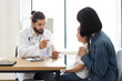 © sofiko14 - Caucasian male doctor offers medicine and pills to sick Caucasian girl and her mother at clinic. Doctor explains treatment options, providing care and comfort.