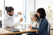 © sofiko14 - Caucasian male doctor explains nebulizer use to sick young girl and mother at clinic. Female child listens attentively as mother supports.