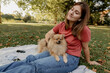 © Westend61 - Young woman with Pomeranian dog relaxing at park