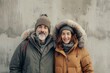 © Markus Schröder - Portrait of a merry caucasian couple in their 40s wearing a warm parka on bare concrete or plaster wall