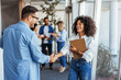 © Dragana Gordic - Smiling Colleagues Shaking Hands in Modern Office Environment