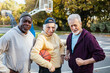 © Marko Geber - Senior men playing basketball outdoors team huddle