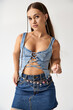 © Bliss - A confident young woman showcases her trendy denim outfit in a stylish studio setting.