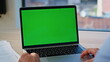 © stockbusters - Freelancer watching greenscreen laptop sitting remote workplace closeup.