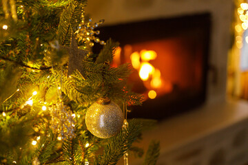 Wall Mural - Beautiful decorated christmas tree with vintage baubles and golden lights on background of burning fireplace. Winter holidays preparation. Atmospheric magical eve. Copy space