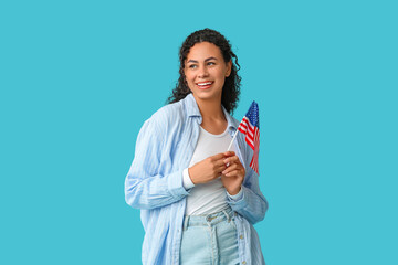 Wall Mural - Beautiful young happy African-American woman with USA flag on blue background