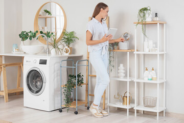 Canvas Print - Young woman with tablet computer in laundry room