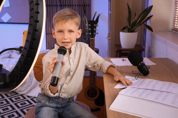 Wall Mural - Cute little boy with microphone recording music video at home