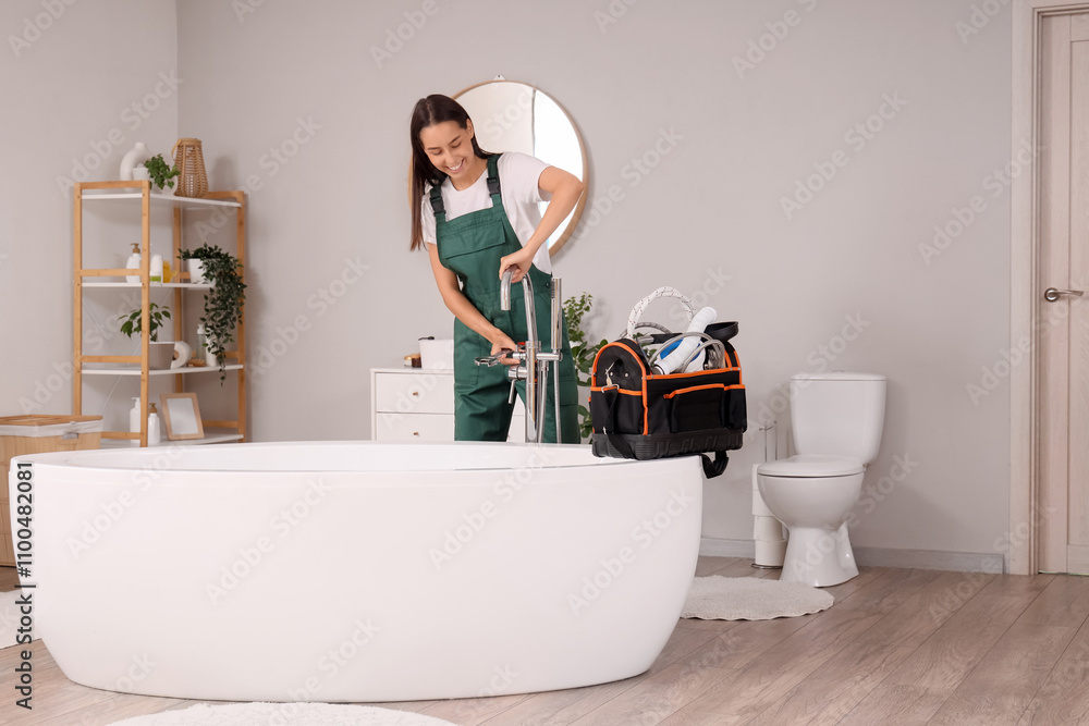 Female plumber fixing bathtub faucet in bathroom