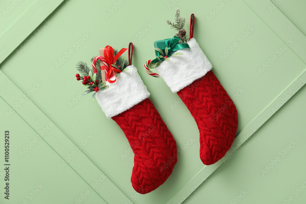 Christmas socks with gifts and decor hanging on green wall
