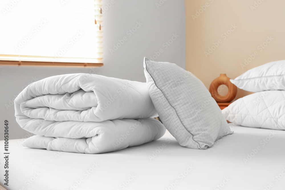 Folded clean blanket and pillow on bed in room