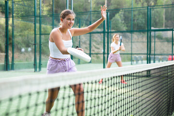 Wall Mural - Caucasian young woman in tank top and shorts playing padel tennis match during training on court.