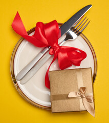 Wall Mural - Round plate and tied fork with knife on yellow background, festive table setting