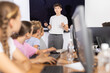 © JackF - Young guy teacher teaches group of children students to work with computer in lesson