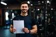 © PulseImages - Smiling fitness instructor ready with training plan in hand, welcoming new clients in a professional gym