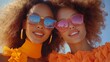 © YURY YUTY - Two women in vibrant attire with sunglasses enjoy a sunny day together outdoors.