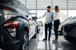 © Zamrznuti tonovi - Couple examining the exterior of luxury car in dealership showroom