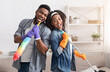 © Prostock-studio - Domestic Band. Joyful Black Couple Having Fun During Spring-Cleaning Home, Singing Together, Using Mop Handle And Duster As Microphones