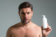 © Volodymyr - Male model hold bottle with dispenser pump for liquid soap, gel or foam. Facial treatment. Beauty portrait of sexy man cosmetics products, beauty and spa. Skincare. Perfect skin, morning routine.