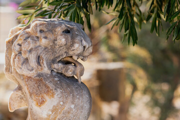 Wall Mural - Close-up of a carved marble lion head sculpture at Bodrum Castle, surrounded by natural greenery, showcasing ancient craftsmanship and detail. Bodrum, Mugla, Turkey (Turkiye)