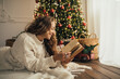 © polinaloves - Young woman reading book, lying near Christmas tree in a cozy decorated room.