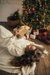 © polinaloves - Young woman reading book, lying near Christmas tree in a cozy decorated room.