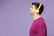 © ViDi Studio - Side profile view young Caucasian man wear violet t-shirt casual clothes listen to music in headphones close eyes isolated on plain pastel light purple background studio portrait. Lifestyle concept.