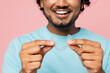 © ViDi Studio - Cropped young smiling Indian man he wear blue t-shirt casual clothes hold in hand invisible transparent aligners, invisalign dental braces isolated on plain pastel pink background. Lifestyle concept.