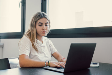 Wall Mural - Young student girl sit at table with textbooks and laptop staring aside, studying alone in library, looks pensive and thoughtful search solution, prepare for exam, makes task feels confused or puzzled