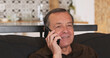 © Oleksii - Senior man smiling talking mobile phone, speak with smartphone cell gadget. Old male friendly happy answering on call. Indoors, living room, portrait