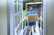 © ungvar - Man is carefully lifting large cardboard box as he exits moving truck, preparing to carry it into his home.