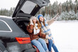 © maxbelchenko - Two young women near a car on a snowy road.  Traveling in Winter.