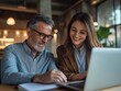 © Photo_hub - A business team of two executives  working together on a laptop in a modern office