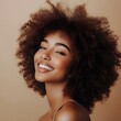 © michaswelt - A woman with natural curly hair smiles warmly against a soft beige background