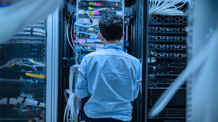 Computer engineer is setting up network in server room,Systems Maintenance Technician,Male engineer working in server room at modern data center