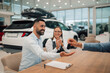 © Zamrznuti tonovi - Couple happily receives car keys from dealer, concluding purchase.