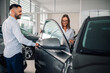© Zamrznuti tonovi - Salesman introduces woman to new vehicle in showroom setting.