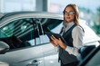 © Zamrznuti tonovi - Focused woman using a tablet for car evaluation in dealership