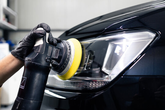 Car detailing and polishing process. Expert polishing car front lights in auto repair shop.
