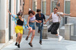 © ADDICTIVE STOCK - Playful friends jumping and laughing in a city setting