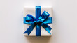© mahamad - Gift box tied with a blue ribbon against a white background.
