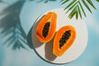 © The Picture Pantry - fresh, ripe papaya sliced ​​open on light blue background, harsh sunlight