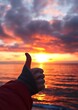 © mobile - thumbs up hand silhouette against stunning sunset over ocean beach