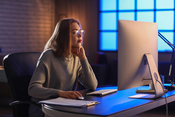 Female programmer working with computer in office at night