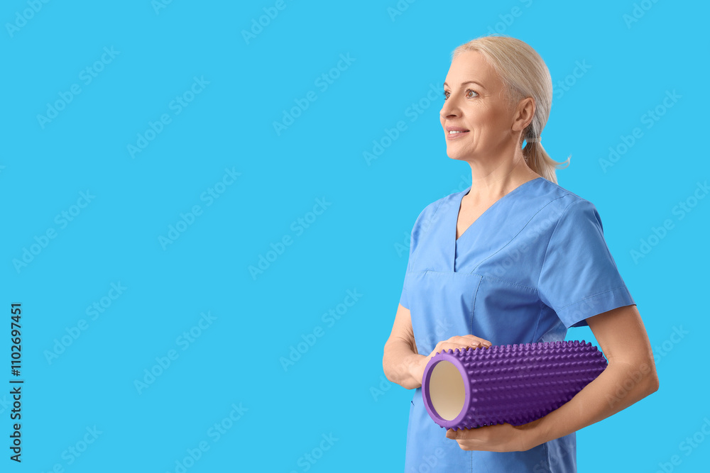Mature physiotherapist with foam roller on blue background