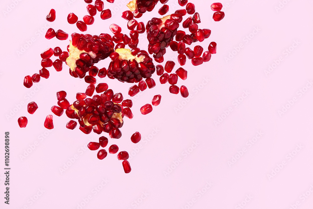 Flying fresh pomegranates with seeds on lilac background